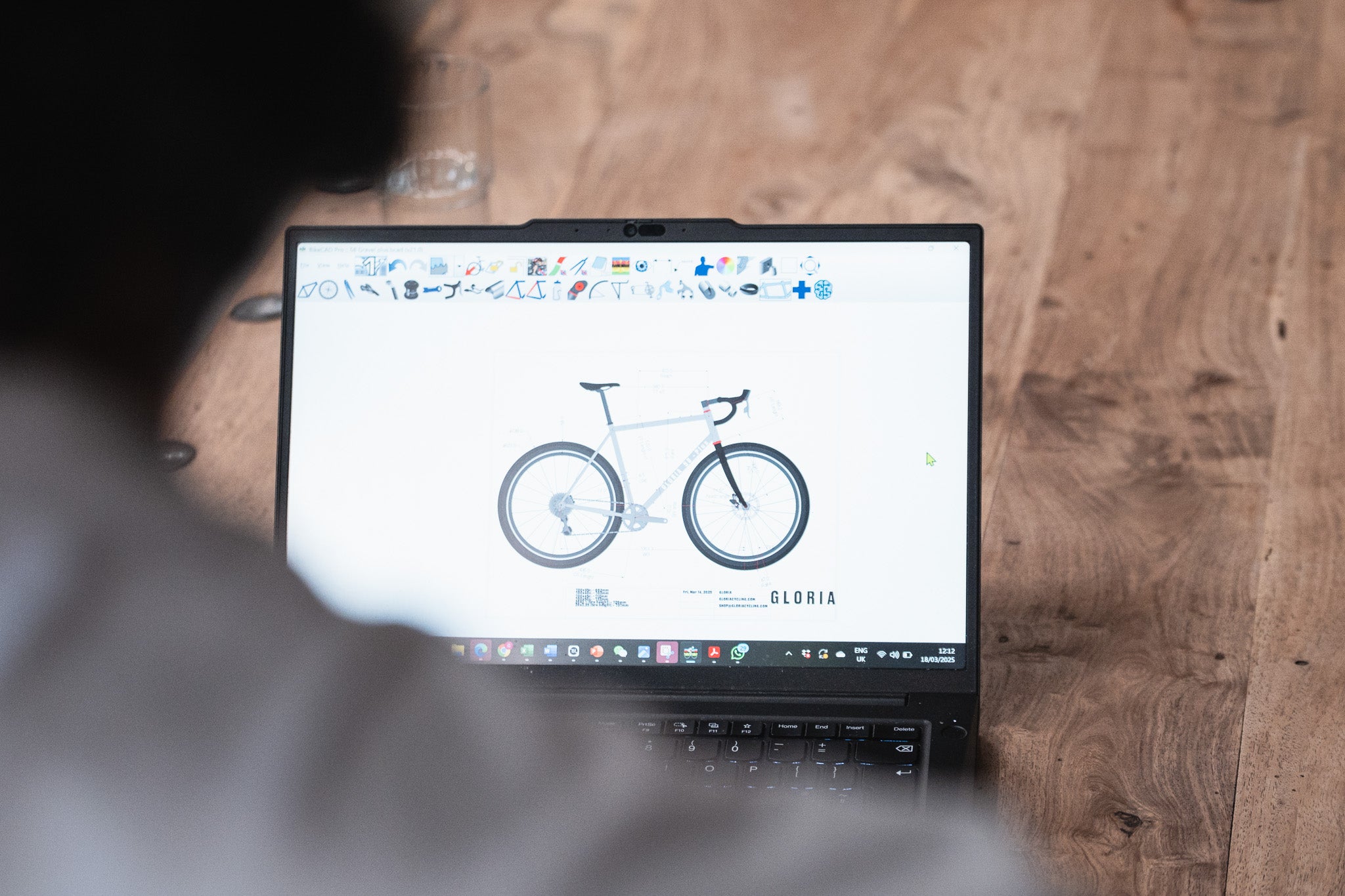 Person using a laptop with a bicycle design on the screen on a wooden desk