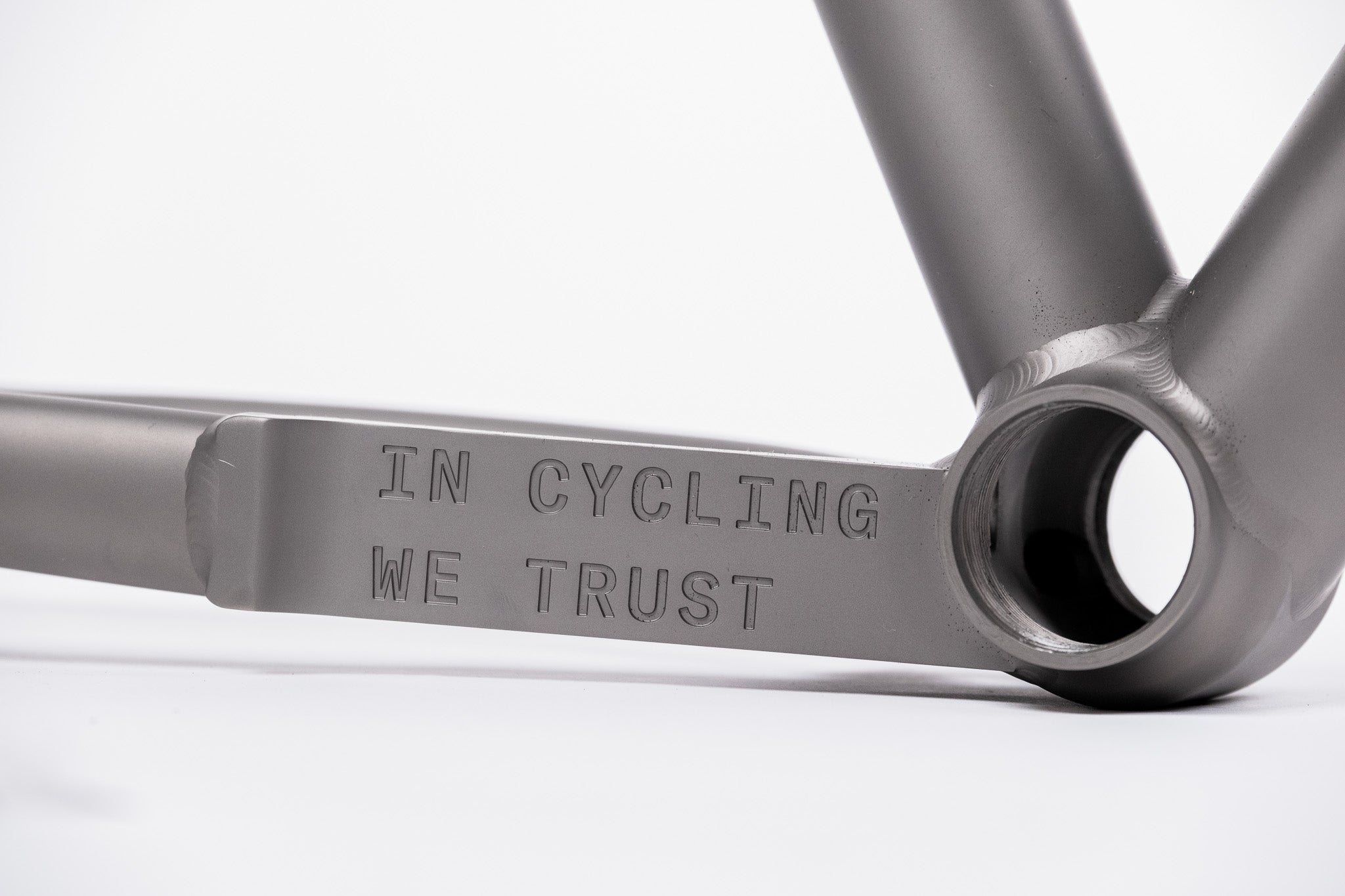 Bicycle frame with 'IN CYCLING WE TRUST' engraving on a white background