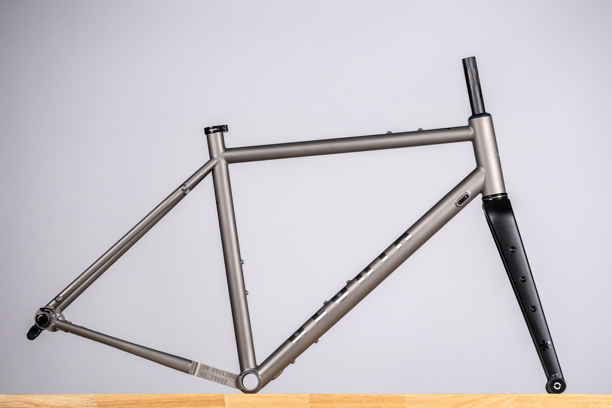 Titanium Bicycle frame on a wooden surface with a gray background