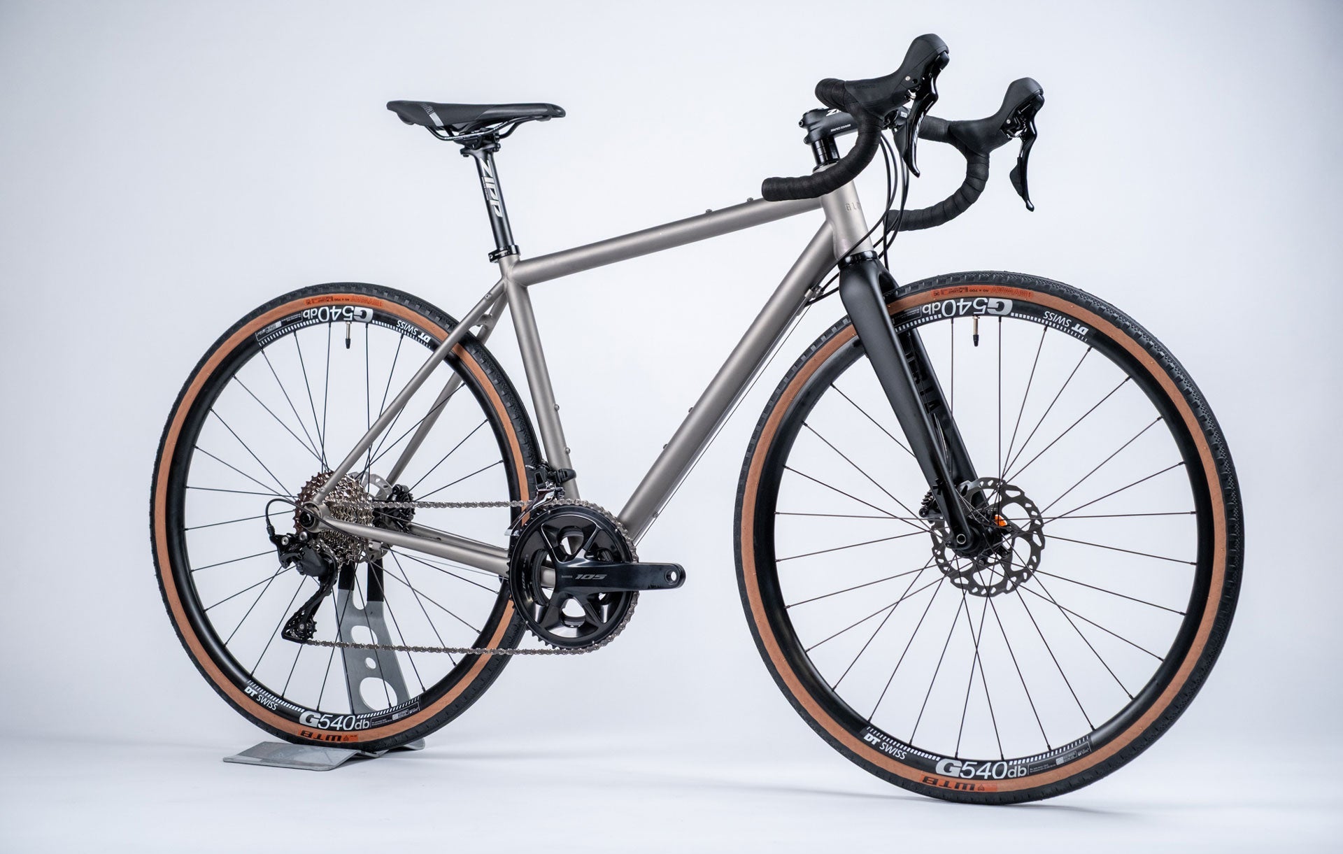 A titanium all-road bicycle with a gray frame and black accents, including DT Swiss wheelset and mechanical groupset by Shimano.