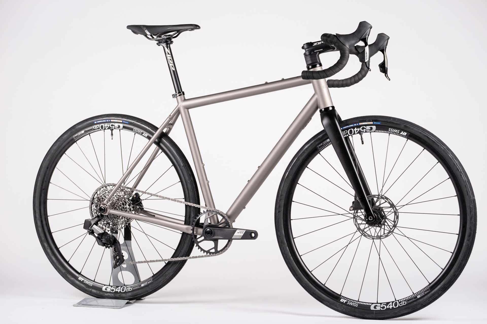 A titanium all-road bicycle with electronic shifting, DT Swiss alloy wheels, and Zipp handlebar and seat post. It features a gray frame and black tires.