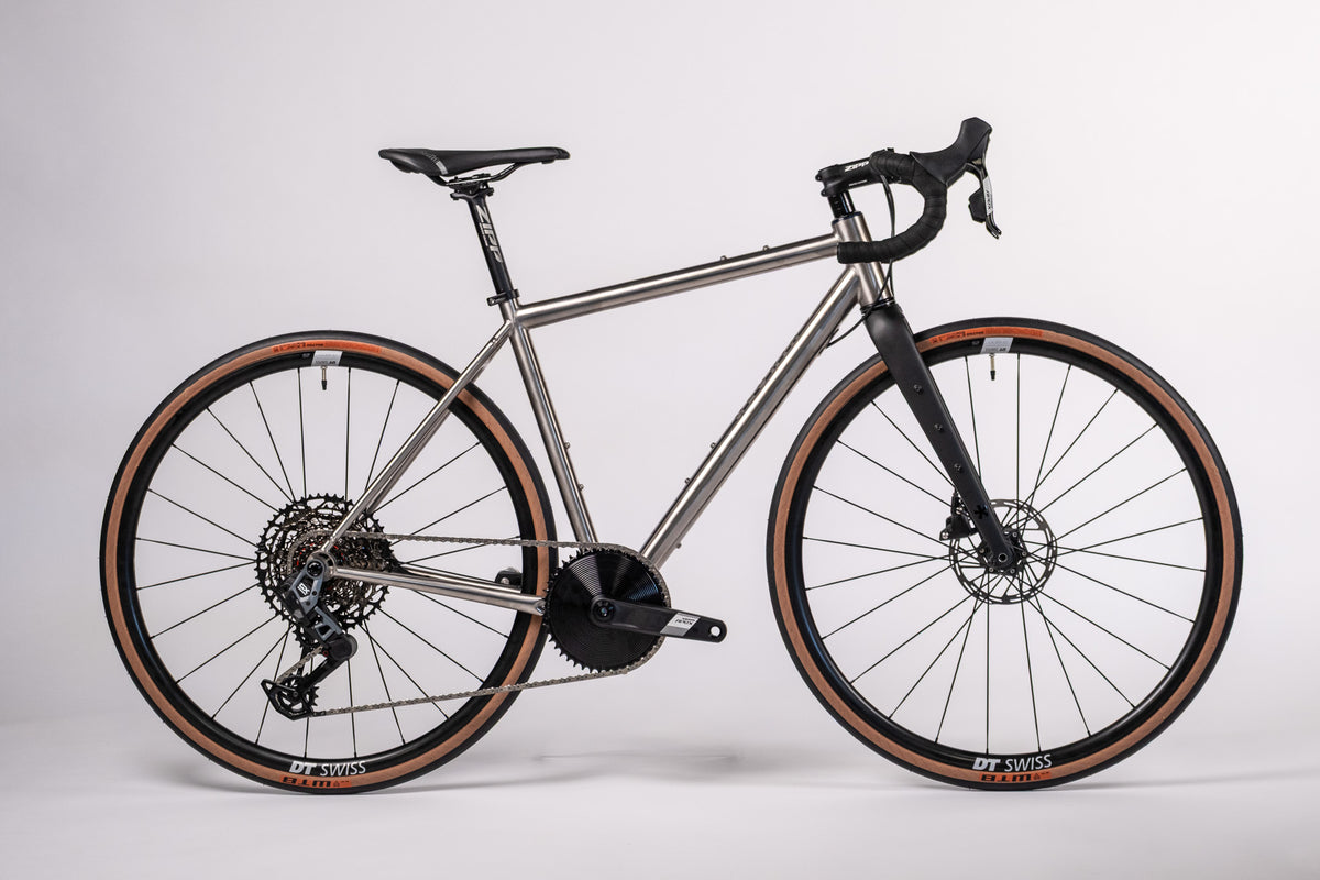 Side view of a Gloria All Road titanium bike with tan-wall tyres and a carbon fork