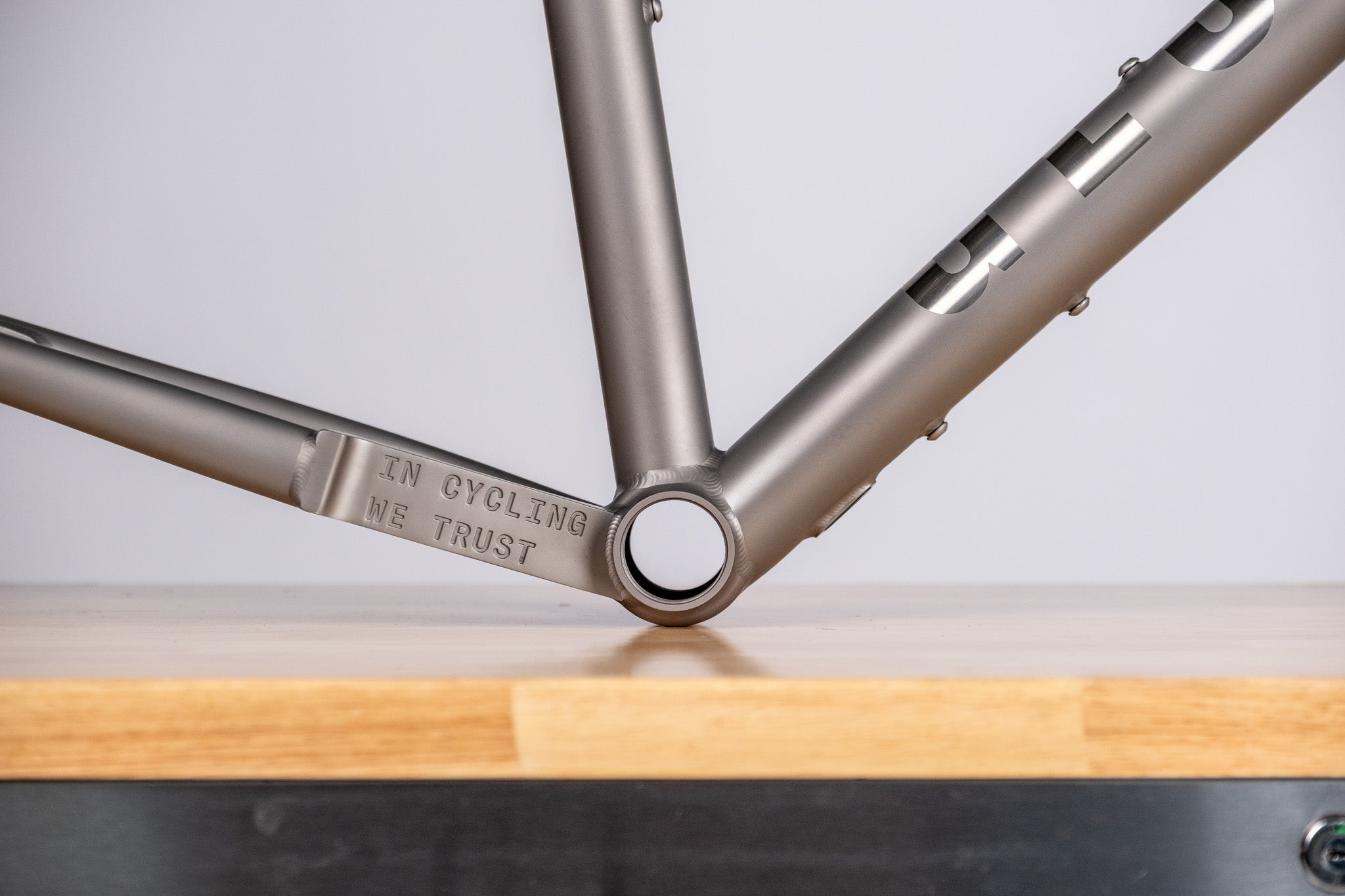  titanium  Bicycle frame with engraved text on a wooden surface and light gray background