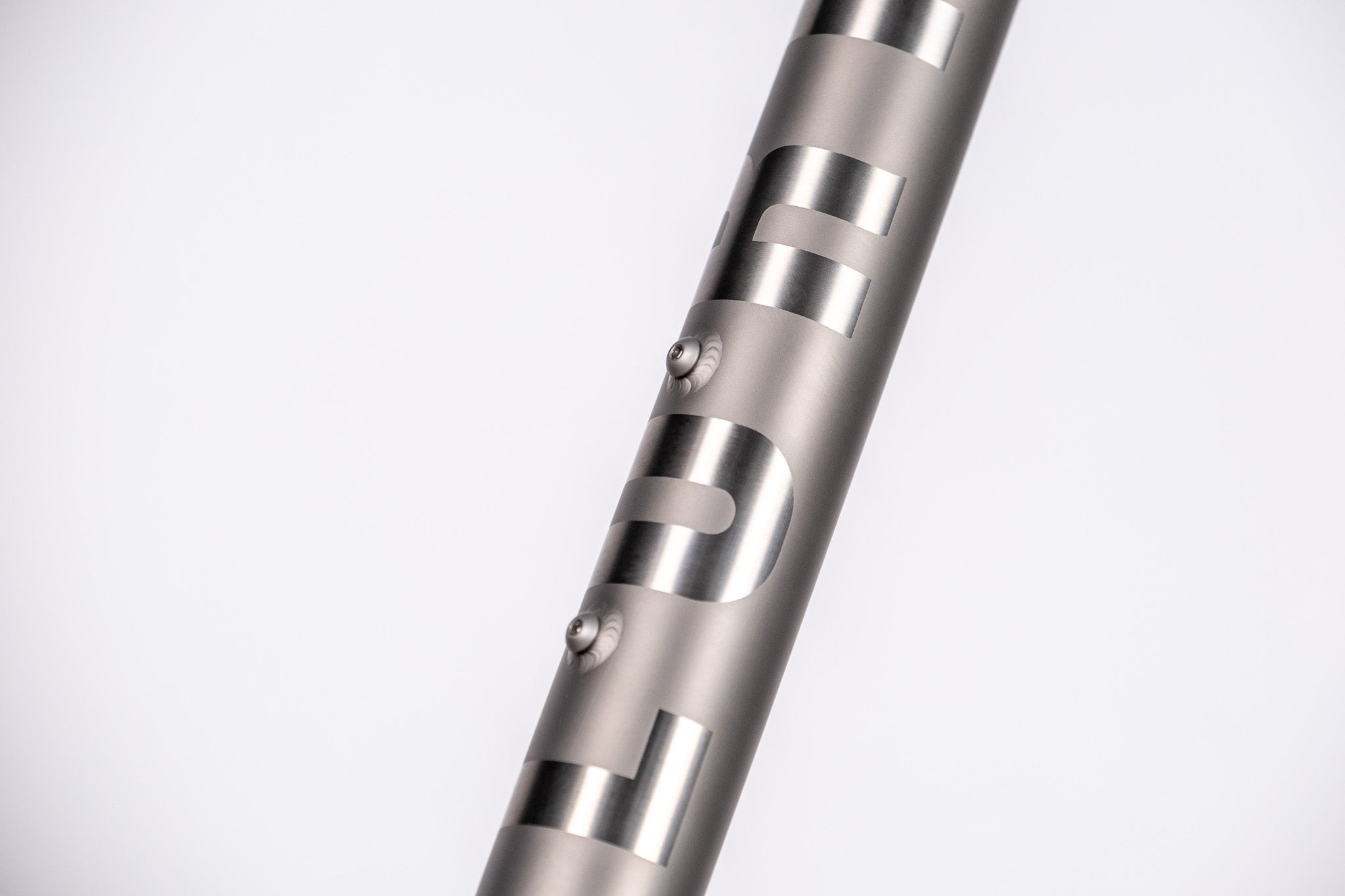 Close-up of a  titanium frame with engraved text on a white background