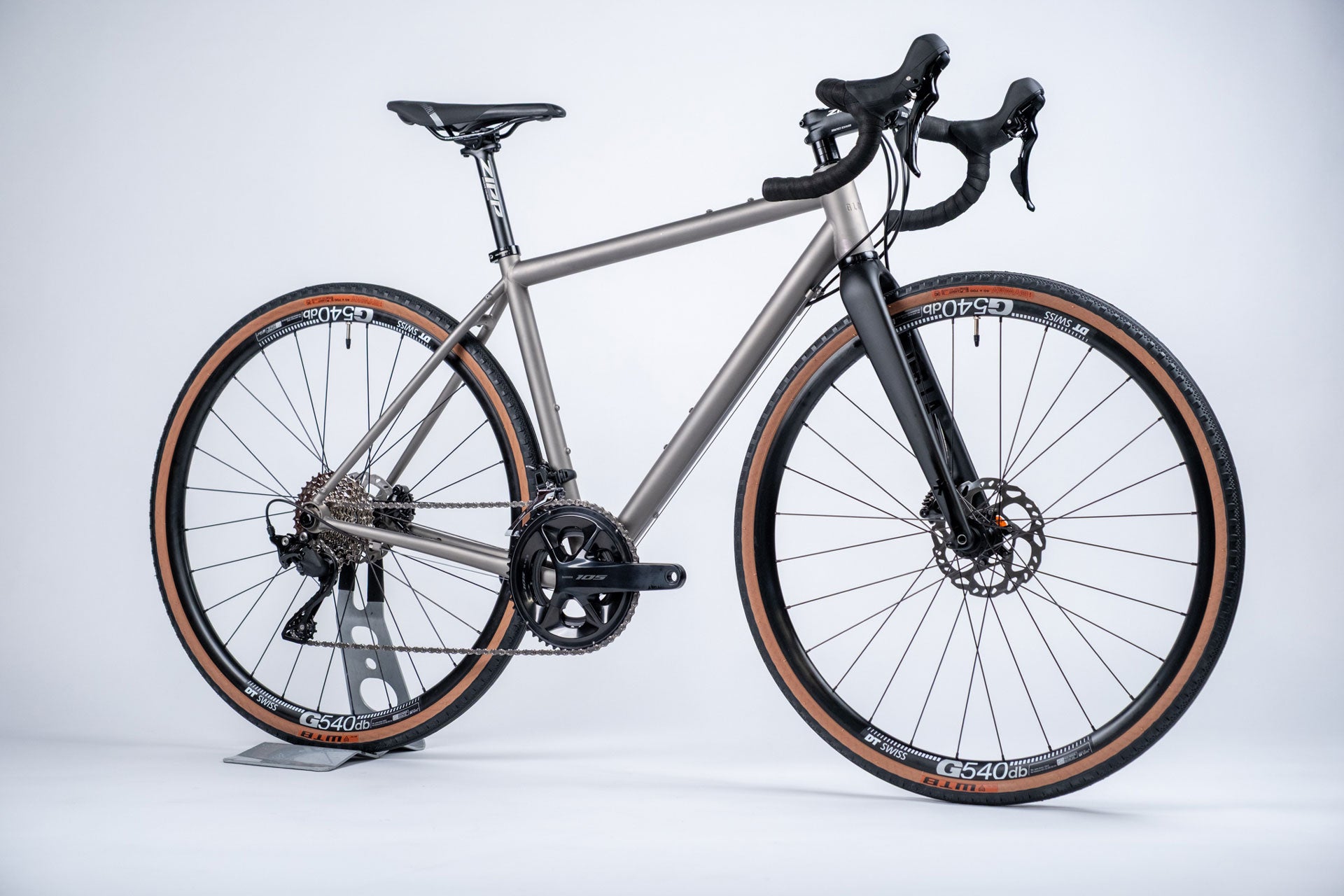 A titanium all-road bicycle with a gray frame and black accents, including DT Swiss wheelset and mechanical groupset by Shimano.