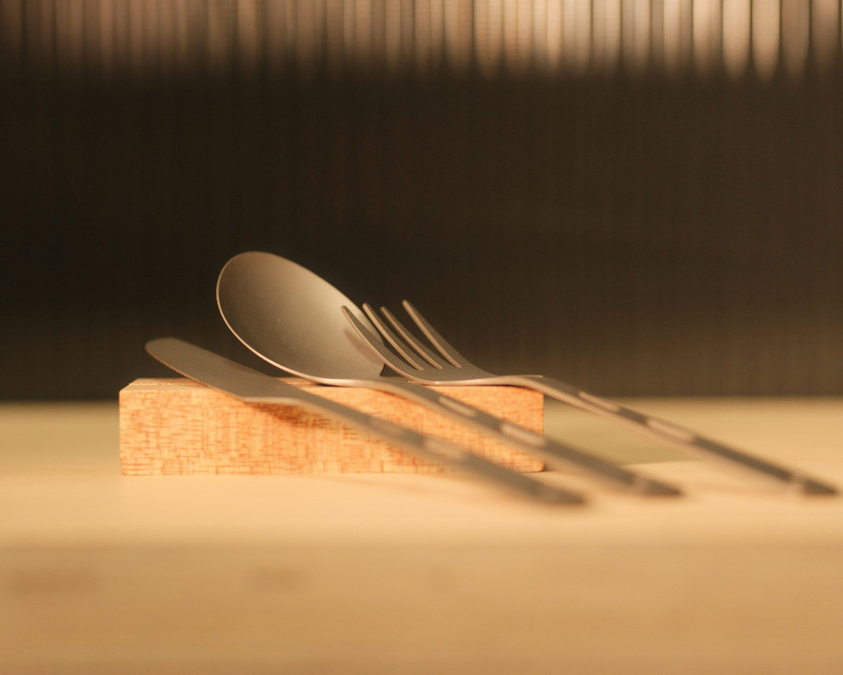 Gloria titanium cutlery set with fork, knife and spoon displayed on a wooden block