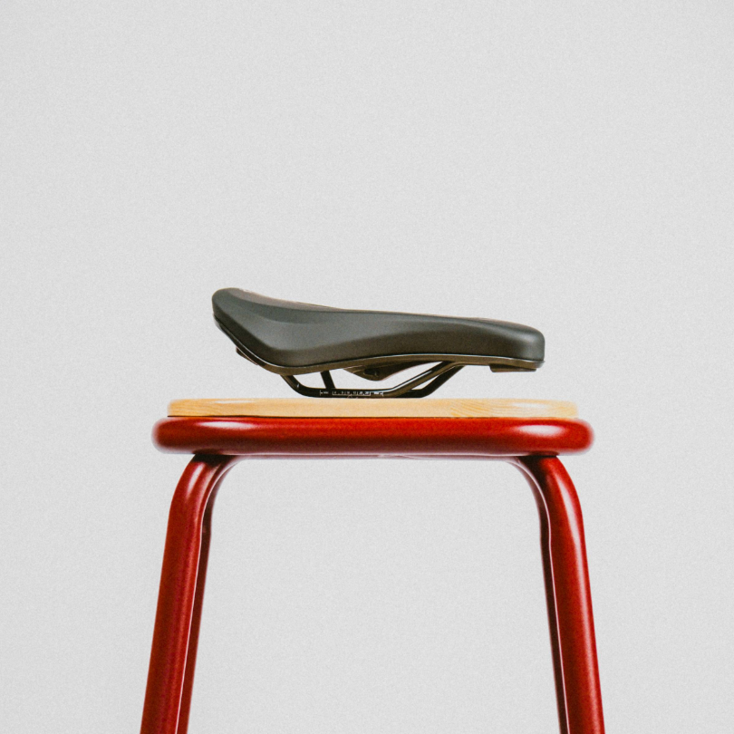 Bicycle seat on a red stool against a light gray background